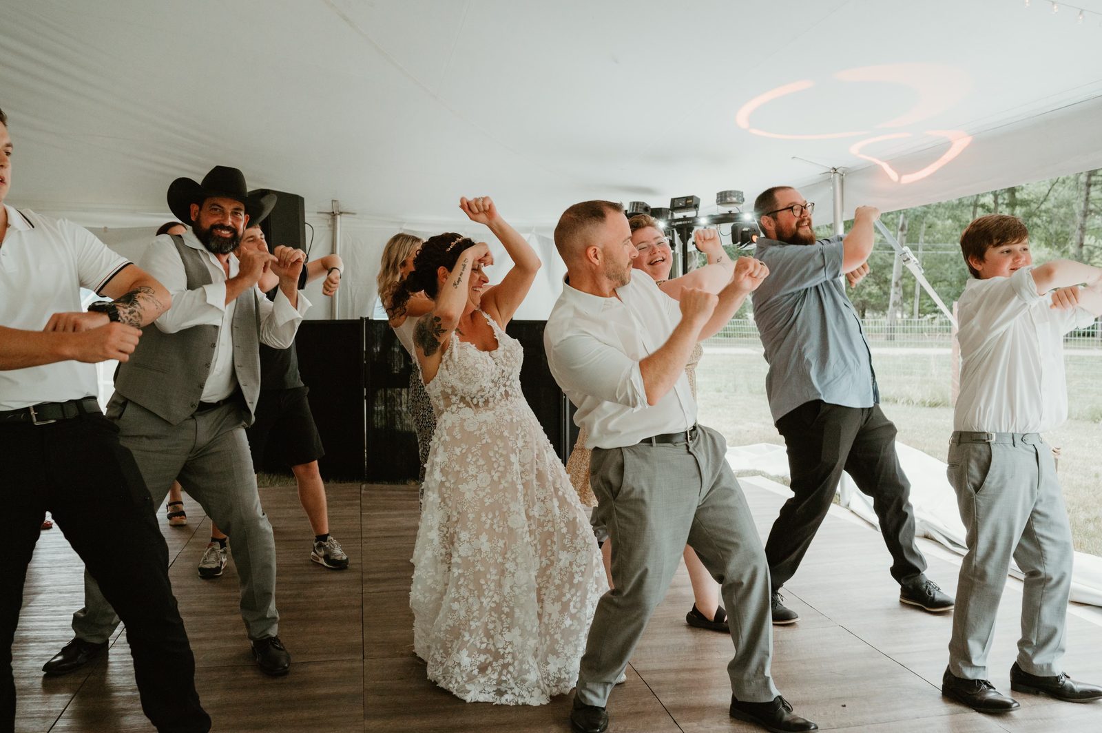 Wedding party dancing under a tent with custom heart-shaped lighting