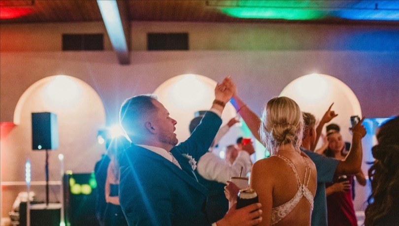 Wedding couple and guests dancing under colorful uplighting at a venue